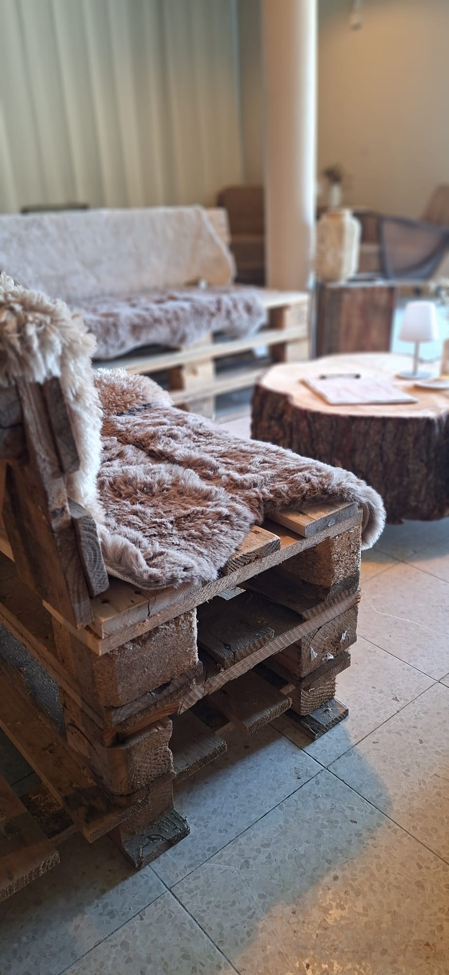 Palettensofa mit Fell und Baumstamm-Tisch in der Lager-Bar Greene